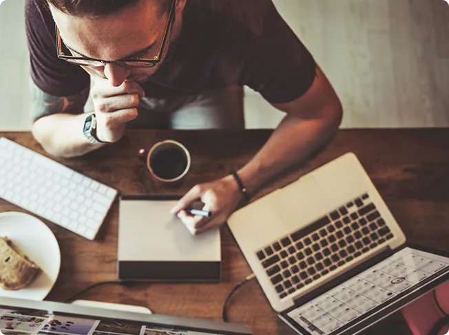 Creator working across multiple devices with coffee
